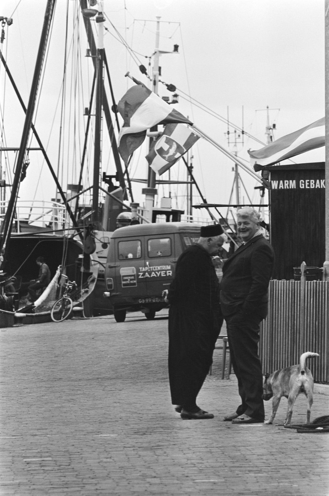 Vissersboten in de haven van Urk met een Urker visserman in traditionele klederdracht op de voorgrond